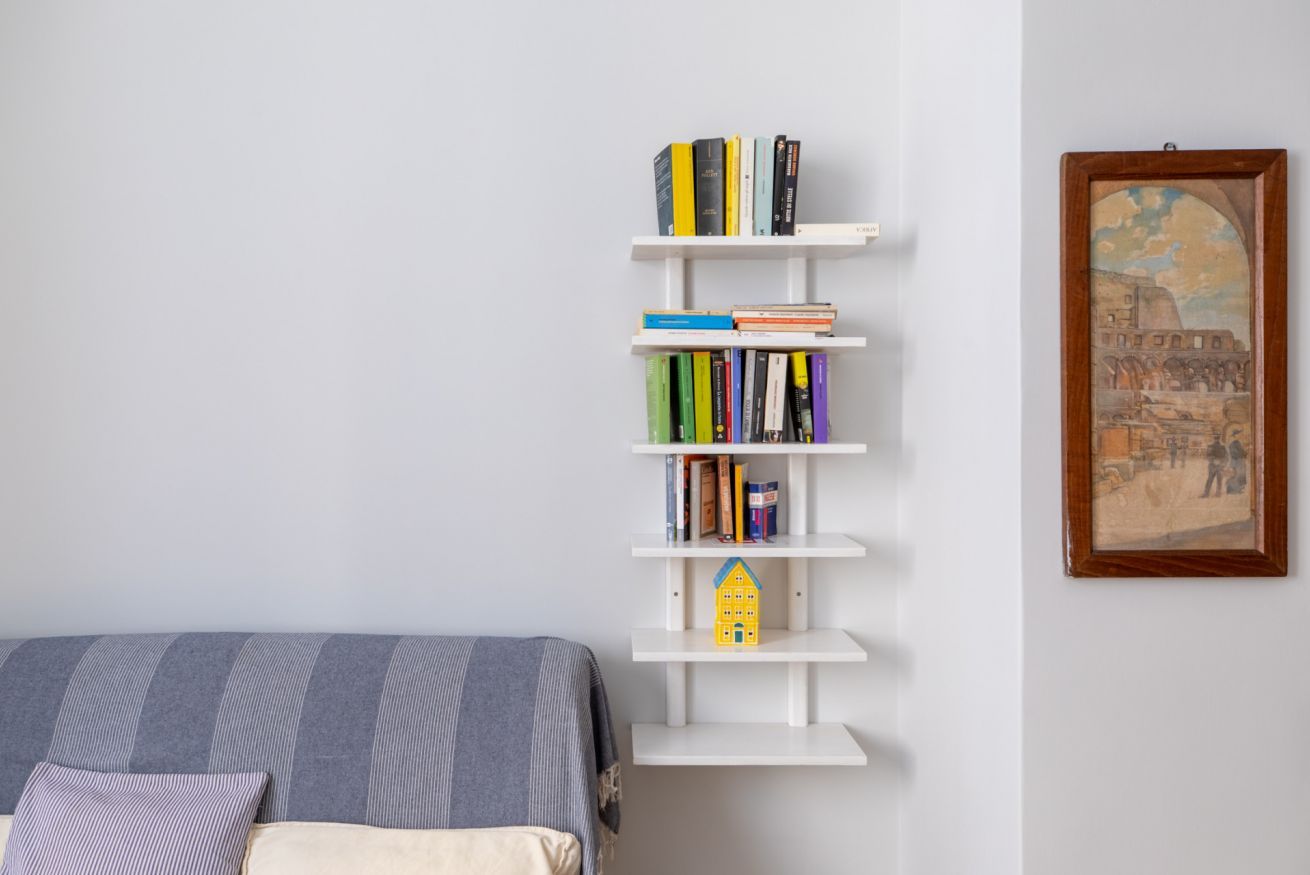 Une chambre à coucher avec un lit, une bibliothèque et un tableau encadré au mur.