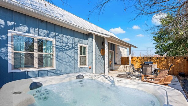Ein Garten mit Whirlpool, Holzterrasse und Gartenmöbeln.