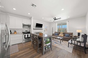 A modern kitchen with white cabinets, a built-in oven, and a dining area with a table and chairs. - Broken Windmill Cottage - Hot Tub, 5 Min to Main (Fredericksburg)