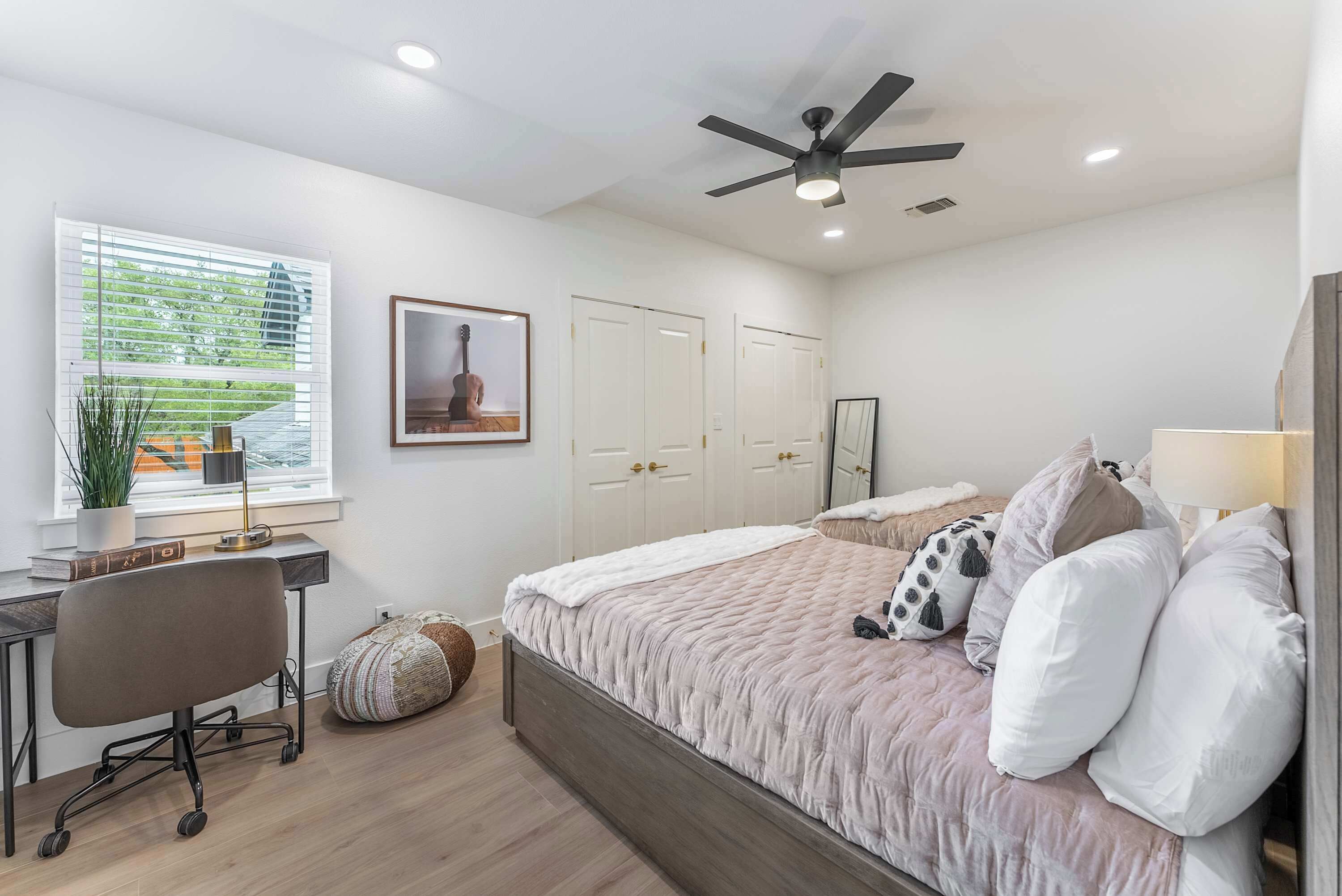Une chambre à coucher comprenant un lit, un bureau, une chaise et un ventilateur de plafond.