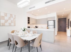 Uma cozinha moderna com ilha central, armários brancos e eletrodomésticos de aço inoxidável.
