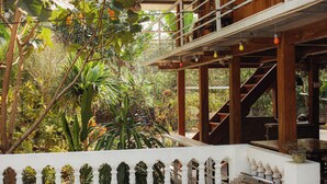 A wooden structure with a balcony, surrounded by lush greenery. - Vietnam Village Homestay (Ha Giang 1)
