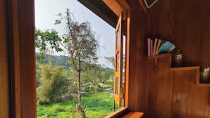 A wooden room with a window, a bed, and a shelf with books. - Vietnam Village Homestay (Ha Giang 1)