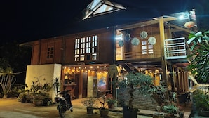 A two-story wooden building with a balcony, potted plants, and a motorcycle parked in front. - Vietnam Village Homestay (Ha Giang 1)