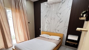 Een moderne slaapkamer met een houten bed, wand met marmerlook en een airconditioning en radiator.