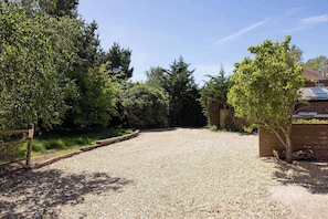 A gravel driveway leading to a brick building with a wooden gate.