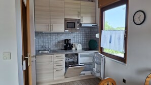 Cocina compacta con microondas, cafetera y lavavajillas, con ventana y vistas.