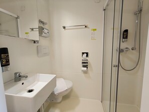 Un baño moderno con lavamanos, inodoro y ducha.