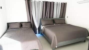 A bedroom with two single beds, a ceiling fan, and a window with curtains.