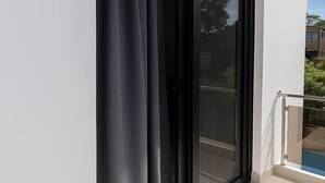 En modern skjutdörr i glas med en svart gardin, som leder ut till en balkong med ett metallräcke.