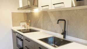 A modern kitchen with stainless steel appliances, a double sink, and a built-in oven. - CAL BOLI COVETES (Margalef de Montsant)