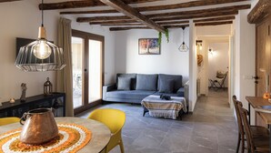 A modern living room with a sofa, a dining table, and a kitchen area. - CAL BOLI COVETES (Margalef de Montsant)