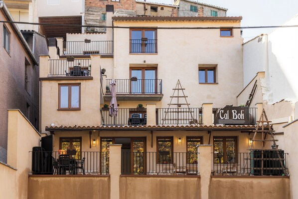 A multi-story building with balconies, a restaurant named 'Cal Boi,' and outdoor seating. - CAL BOLI COVETES (Margalef de Montsant)
