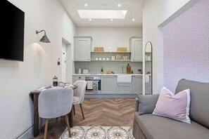 Ett kompakt bostadsutrymme med ett litet kök, en matplats och en sittgrupp.