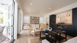 A modern living space with a sofa, chairs, a coffee table, and a kitchen area with cabinets and a stove. - Beautiful Montecito Beach House. Stones throw away from Butterly Beach (Montecito)