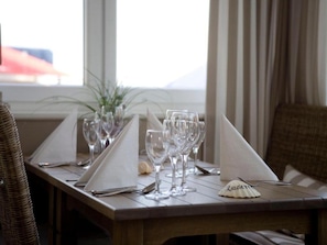 A dining table set with wine glasses, cutlery, and a menu. - Heikendorf Corner Junior Suite Sea Side (Heikendorf)