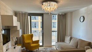 Ein modernes Wohnzimmer mit einer Couch, einem gelben Sessel und einer Chandelier.