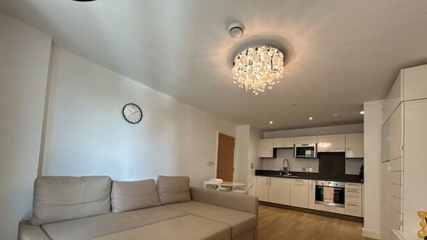 Ein modernes Wohnzimmer mit Sofa, einem Esstisch und einer Küche im Hintergrund.