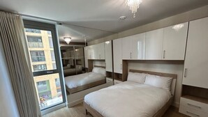 Ein Schlafzimmer mit einem großen Bett, einem Kleiderschrank und einer Glastür zum Balkon.