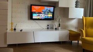 Ein modernes Wohnzimmer mit einem an der Wand befestigten Flachbildfernseher, einer weißen Unterhaltungsanlage und einem gelben Sessel.
