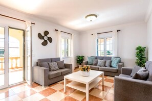 A living room with two sofas, a coffee table, and a decorative fan. - Villa Marques by Villa Plus (Cala en Porter)