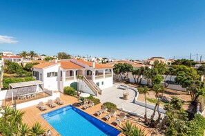 Zona residencial con piscina, sillas de descanso y una escalera que lleva a un edificio.