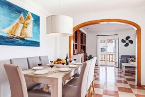 Ein Essbereich mit einem Holztisch, gedeckt für vier Personen, einem Segelboot-Bild an der Wand und Blick in den angrenzenden Wohnbereich.