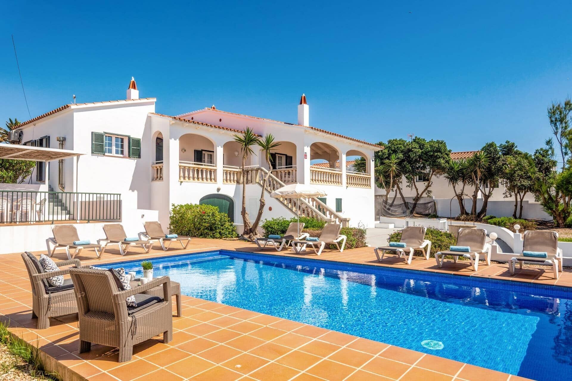 A poolside area with lounge chairs and a clear blue pool.