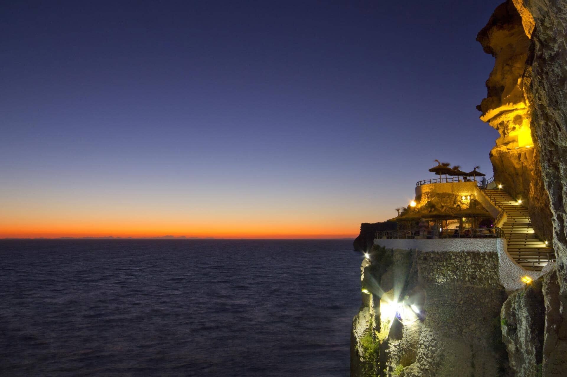Un hôtel situé au bord d’une falaise, avec un escalier menant à une plateforme d’observation d’où l’on peut admirer la mer.