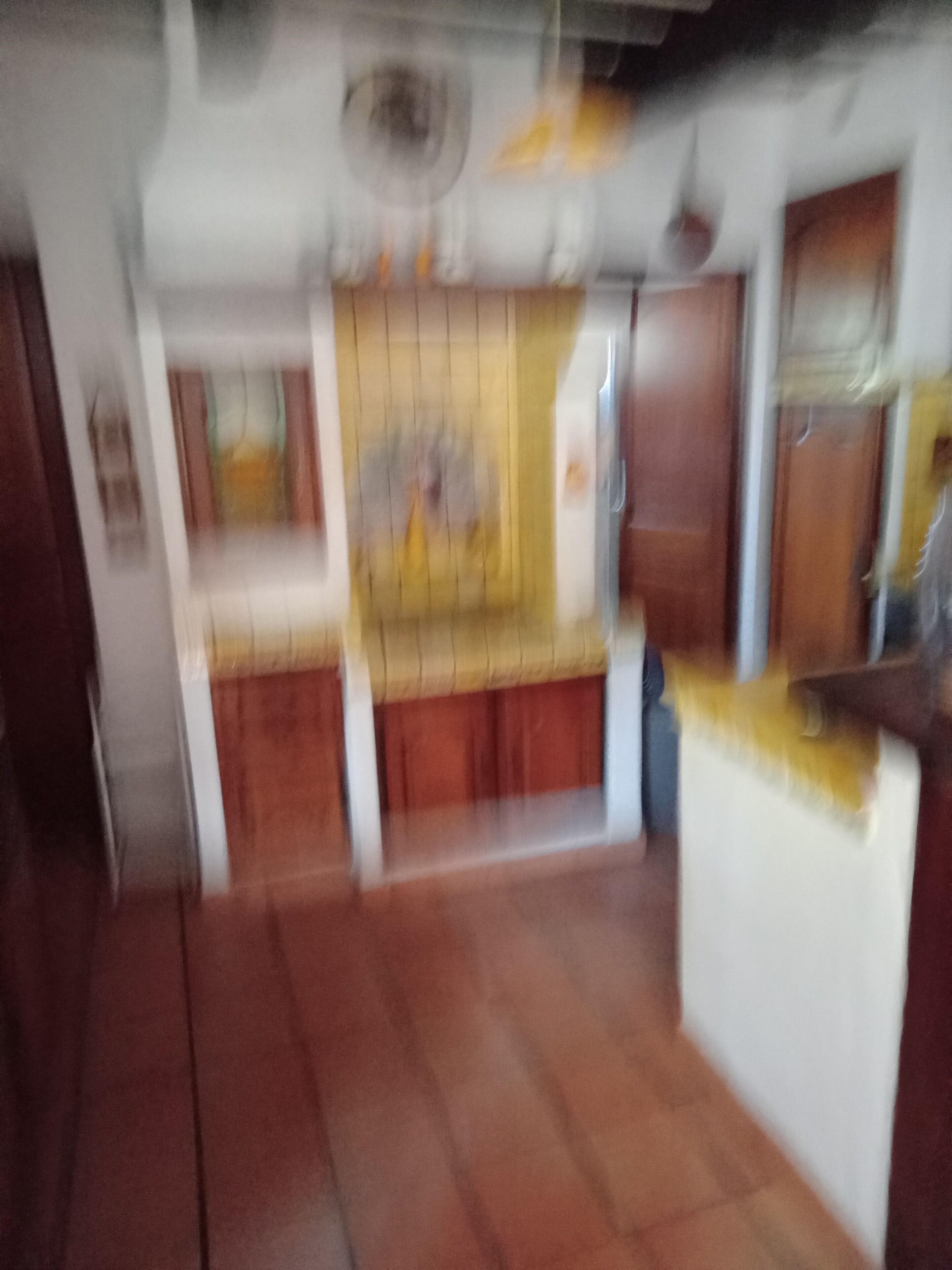 A room with a wooden floor, a white wall, and a window with a curtain.