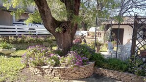 A stone pathway leading to a tree with a stone planter filled with flowers. - Villa with spa pool 2.5 km from the sea Poolhouse barbecue (La Seyne-sur-Mer)