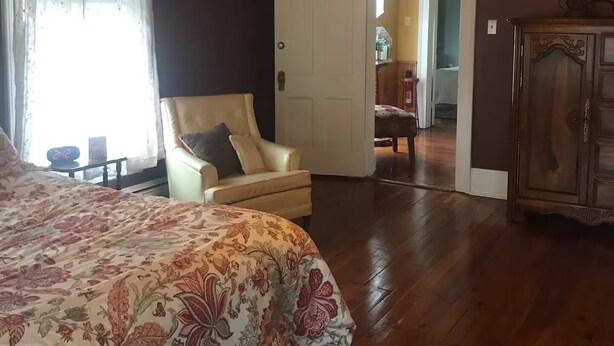 A bedroom with a bed, a chair, a wardrobe, and a door leading to another room. - Perfect for Everyone - 8-bedrooms - The Future Generations University Guesthouse (Franklin)