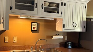 A kitchen with two sinks, a stove, cabinets with glass doors, and a framed sign on the wall. - Perfect for Everyone - 8-bedrooms - The Future Generations University Guesthouse (Franklin)