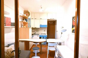 A compact kitchen with white cabinets, a small dining table, and a single chair. - M453 - Marcelli, comfortable two-room apartment with garden (Marcelli)