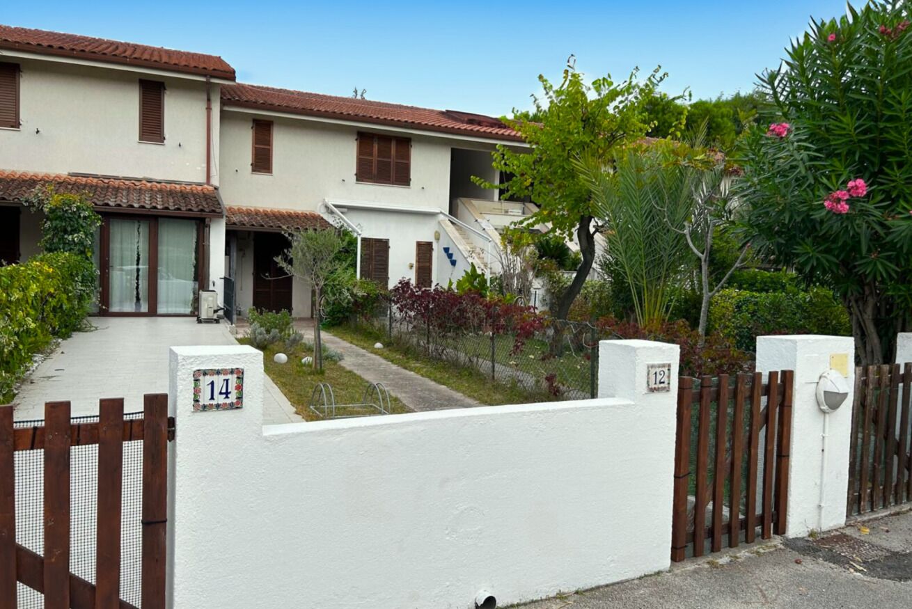 A residential building with a white facade, brown shutters, and a tiled roof.