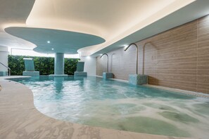 An indoor swimming pool with a curved design, tiled walls, and a wooden floor. - Golfside 3BR Apt with large Terrace, Pool & Spa (Mijas)