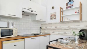 A compact kitchen with white cabinets, a microwave, a kettle, and a small refrigerator. - Functional Studio | Air Conditioning | Space to work (Kraków)