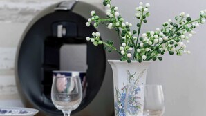 A table with a white vase with blue floral patterns, a clear glass, and a plate with a blue pattern. - Functional Studio | Air Conditioning | Space to work (Kraków)