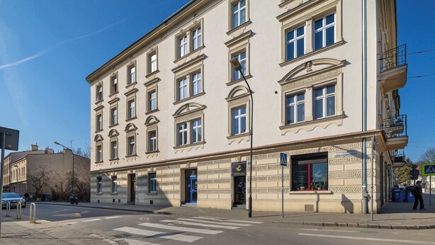 A multi-story building with a classic architectural style, featuring a ground-floor entrance with a sign, a visible staircase, and a balcony on the right side. - Functional Studio | Air Conditioning | Space to work (Kraków)