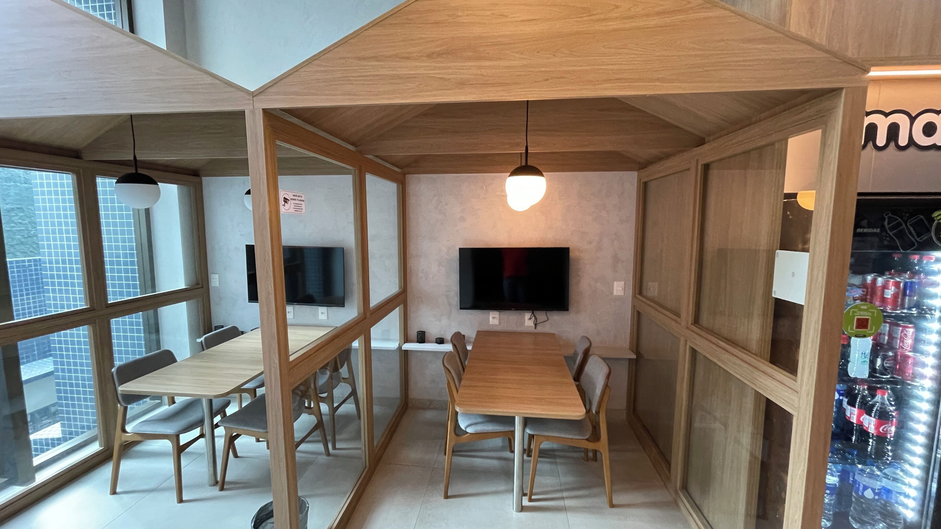 Ein moderner Konferenzraum mit großem Tisch, Stühlen, einem Flachbildfernseher und einer Verkaufsmaschine.