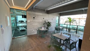 Un espacio interior moderno con paredes de vidrio, una zona de recepción y asientos exteriores con vistas.