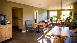 A spacious room with a dining area, a sofa, and a kitchen area. - Hotel de Horper Wielen (Kaard)