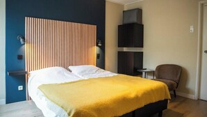A bedroom with a bed, bedside tables, a chair, and a wall-mounted TV. - Hotel de Horper Wielen (Kaard)