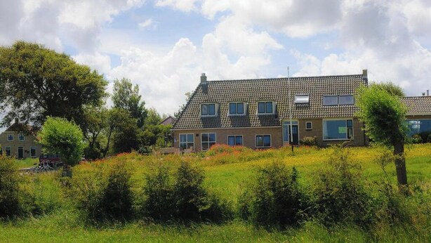 A two-story house with a tiled roof, multiple windows, and a garden in front. - Hotel de Horper Wielen (Kaard)