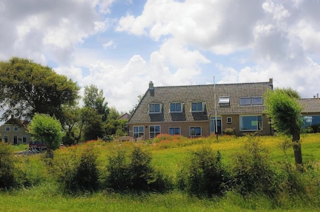 A two-story house with a tiled roof, multiple windows, and a garden in front.