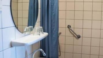 Un baño con lavamanos blanco, espejo y ducha con cortina.