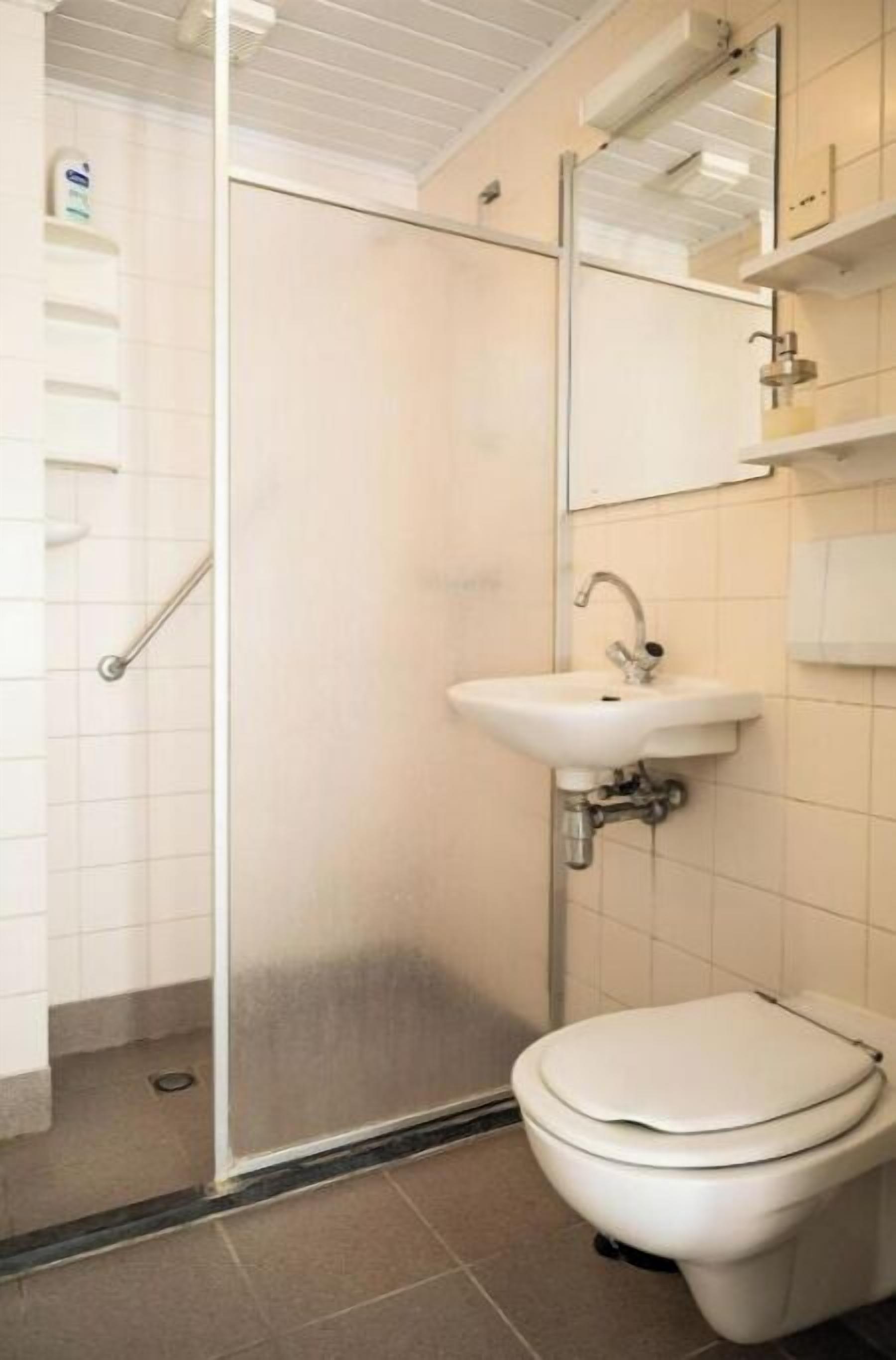 A bathroom with a toilet, sink, and shower.