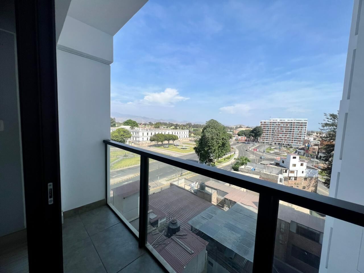 A balcony with a clear view of a cityscape, including buildings and a road.