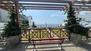 Una pergola in legno con una panca, piante in vaso e vista sul mare.