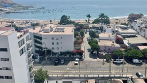 Paesaggio costiero con un edificio bianco imponente, una spiaggia e una vista limpida sull'oceano.